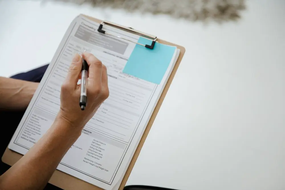 A hand completing a form on a clipboard