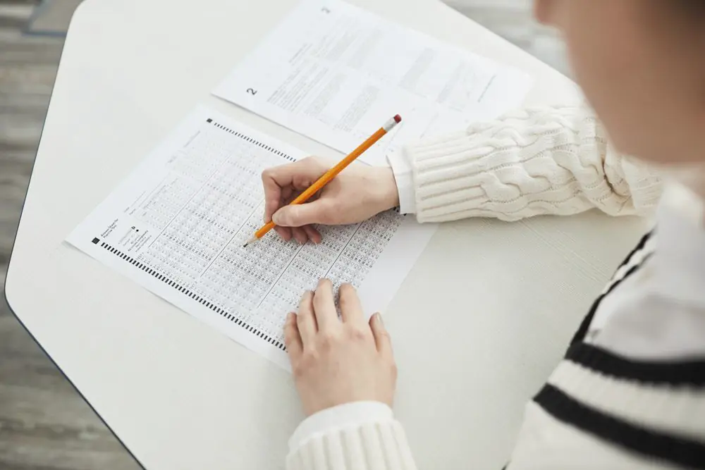 Hands completing an answer sheet with a pencil